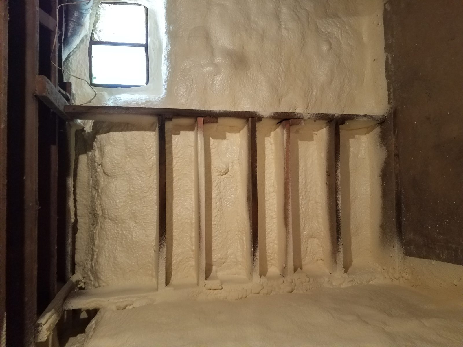 Applicator spraying closed-cell foam in a building
